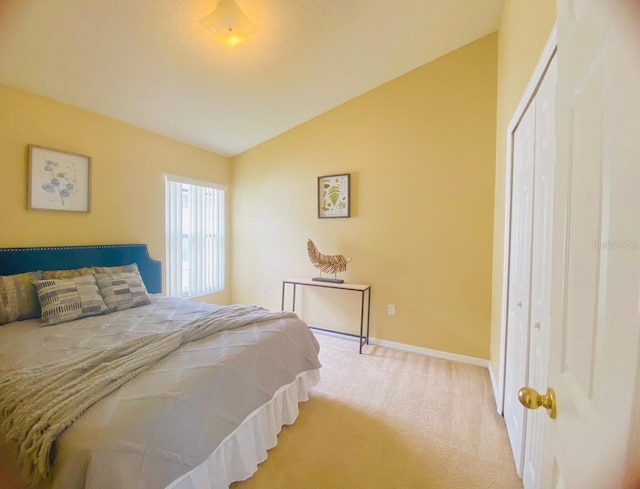 bedroom featuring light carpet, vaulted ceiling, and a closet