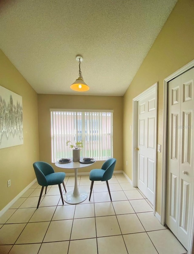 sitting room featuring a textured ceiling, vaulted ceiling, and light tile floors