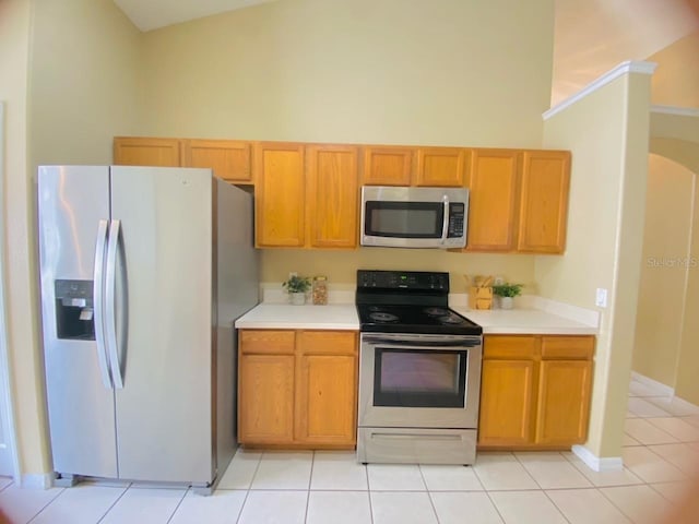 kitchen featuring high vaulted ceiling, light tile flooring, and appliances with stainless steel finishes