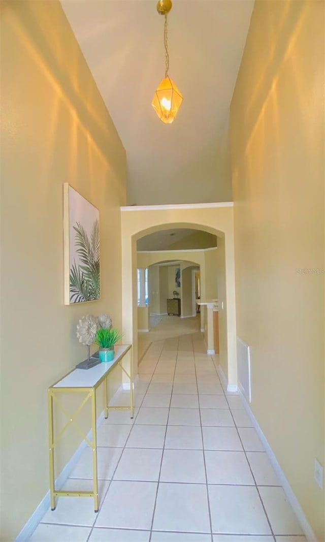 hall featuring high vaulted ceiling and light tile flooring