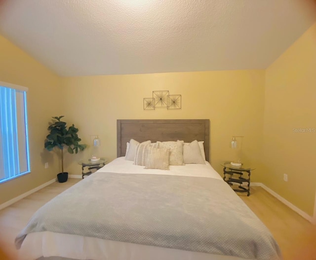 bedroom with light carpet, a textured ceiling, and vaulted ceiling