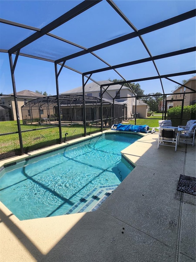 view of pool with glass enclosure, a yard, and a patio