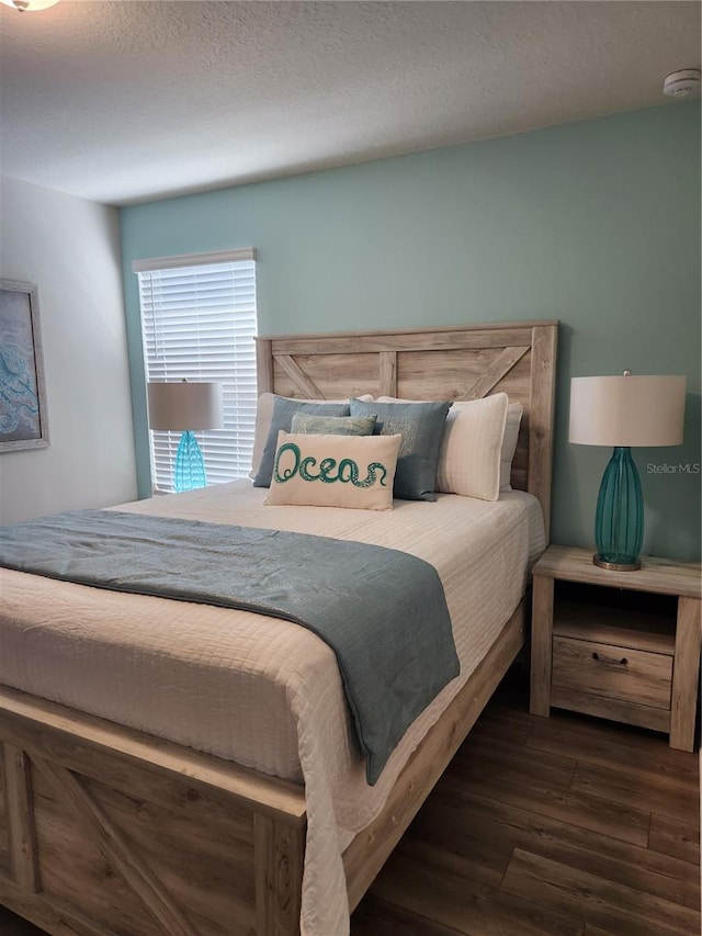 bedroom with dark hardwood / wood-style floors and a textured ceiling