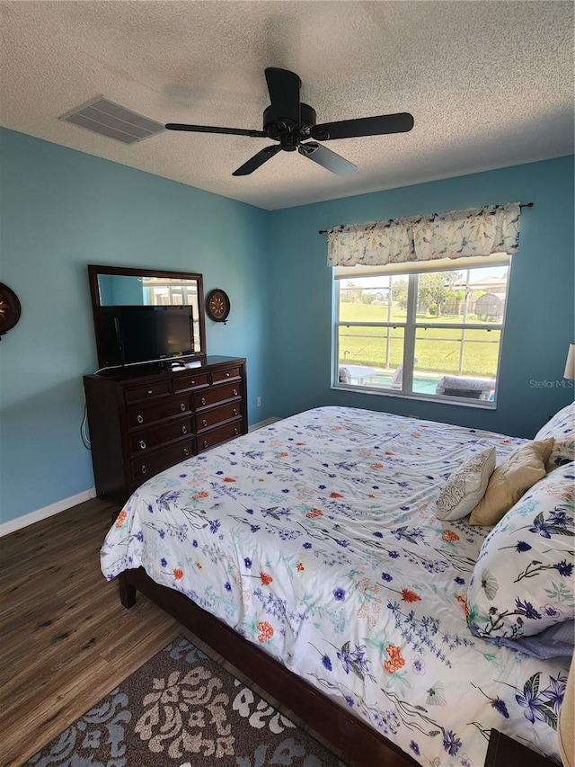 bedroom with a textured ceiling, dark hardwood / wood-style flooring, and ceiling fan