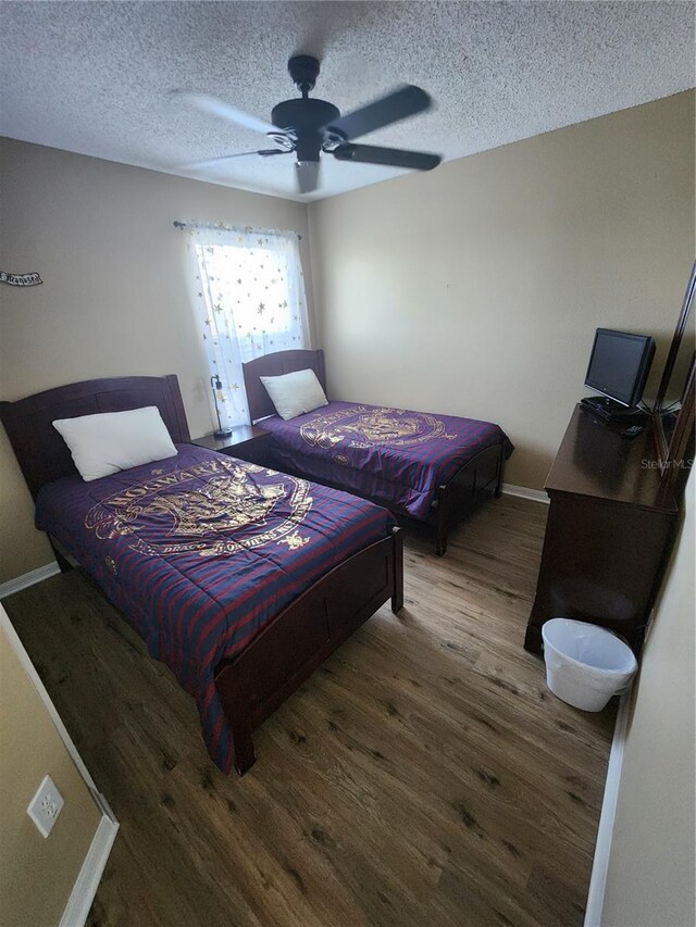 bedroom featuring dark hardwood / wood-style flooring, a textured ceiling, and ceiling fan