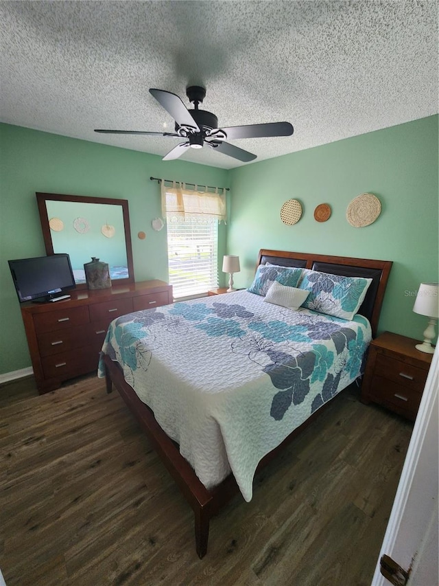 bedroom with a textured ceiling, ceiling fan, and dark wood-type flooring