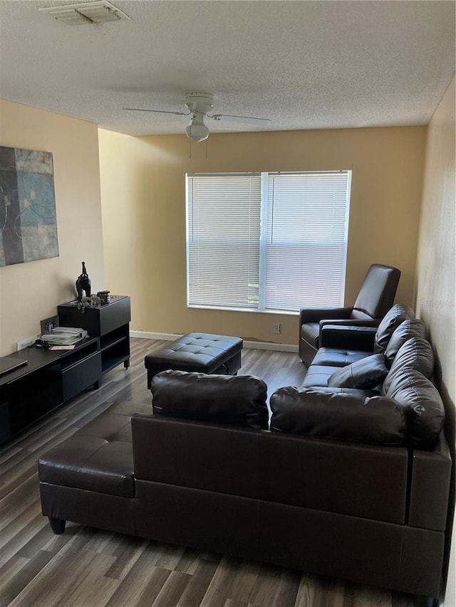 living room with a textured ceiling, wood-type flooring, and ceiling fan