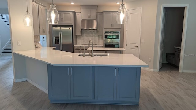 kitchen with light hardwood / wood-style flooring, kitchen peninsula, tasteful backsplash, stainless steel appliances, and pendant lighting