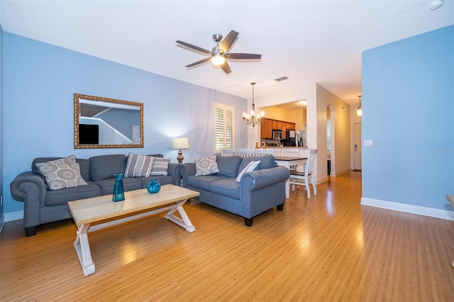 living room featuring light hardwood / wood-style flooring and ceiling fan with notable chandelier