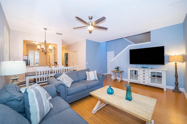 living room featuring light hardwood / wood-style flooring and ceiling fan with notable chandelier