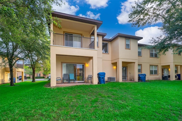 rear view of property with a balcony, central AC unit, a yard, and a patio area