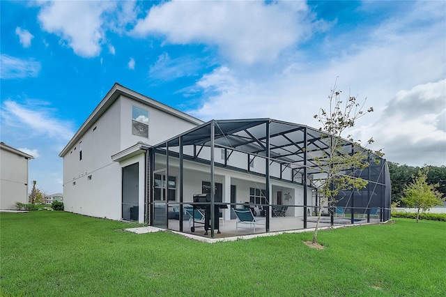 back of house featuring a lawn, glass enclosure, and a patio area