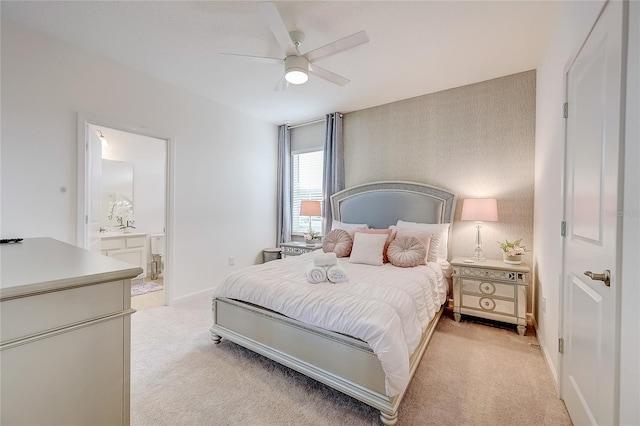 bedroom with ceiling fan, light colored carpet, and connected bathroom