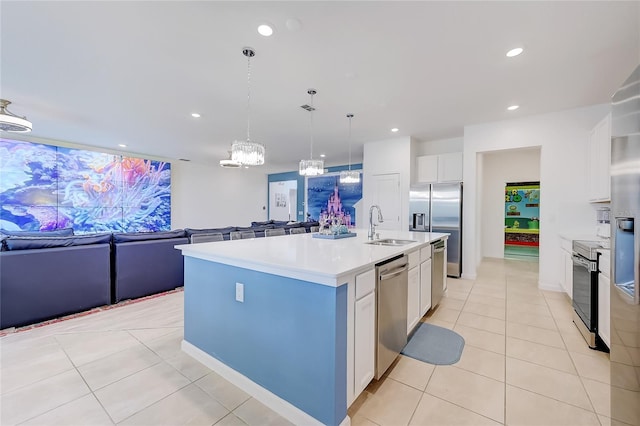 kitchen with a kitchen island with sink, stainless steel appliances, hanging light fixtures, white cabinets, and sink