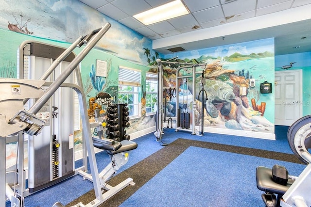 workout area featuring a paneled ceiling and dark colored carpet