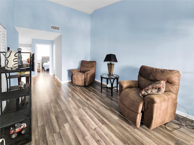 living area with a towering ceiling and dark hardwood / wood-style floors