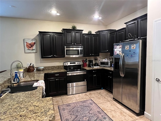 kitchen with light stone counters, stainless steel appliances, sink, and light tile patterned floors