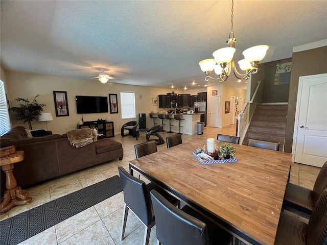 tiled dining space with ceiling fan with notable chandelier and a textured ceiling