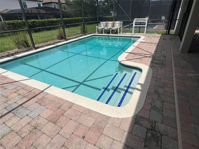 view of swimming pool featuring glass enclosure and a patio area