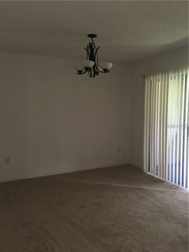 unfurnished room featuring carpet floors and a notable chandelier