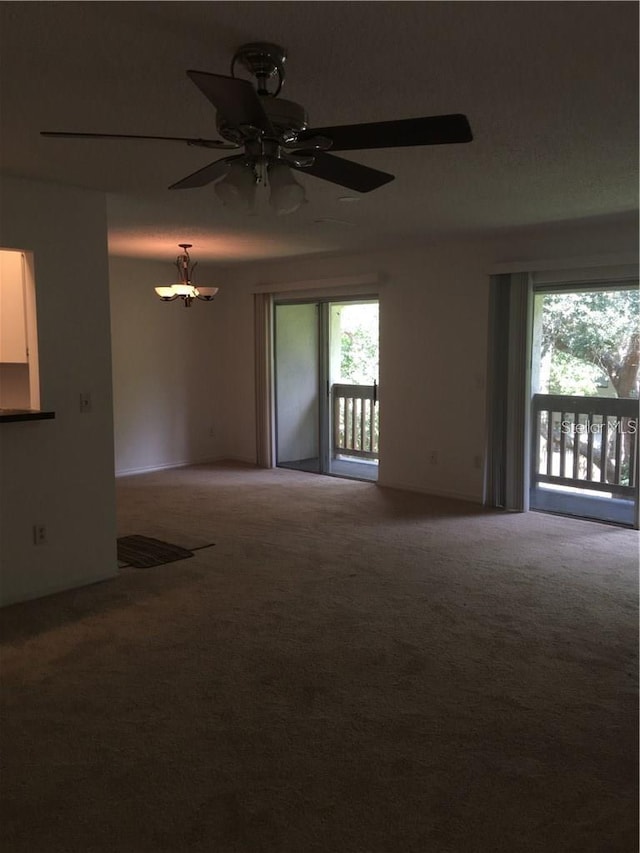 spare room featuring ceiling fan with notable chandelier and carpet floors