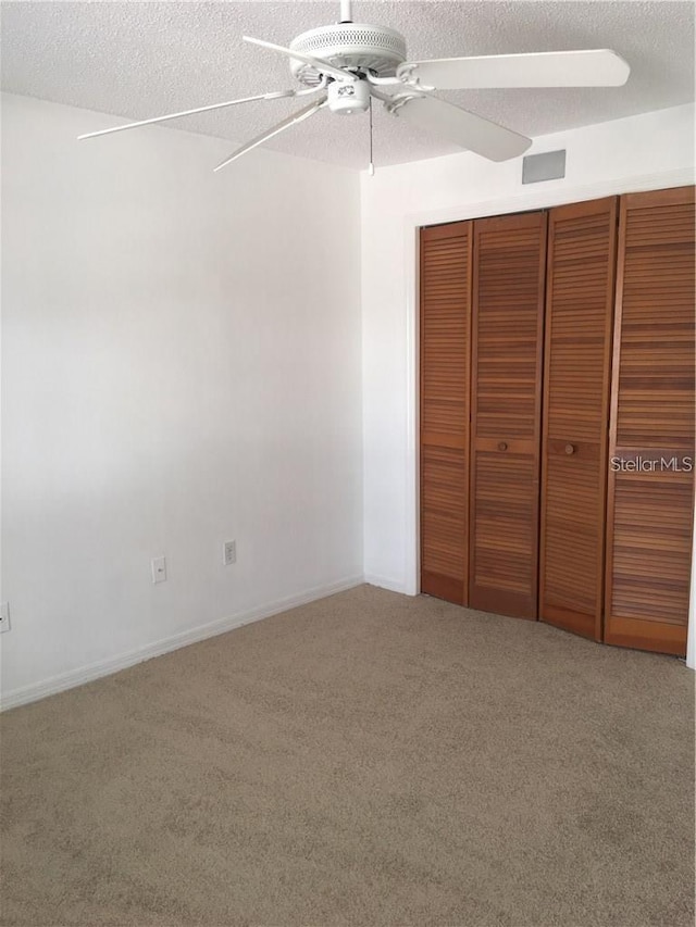 unfurnished bedroom with ceiling fan, carpet flooring, a textured ceiling, and a closet