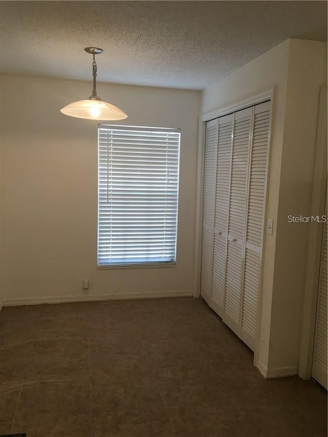 unfurnished bedroom featuring a closet, dark carpet, and a textured ceiling