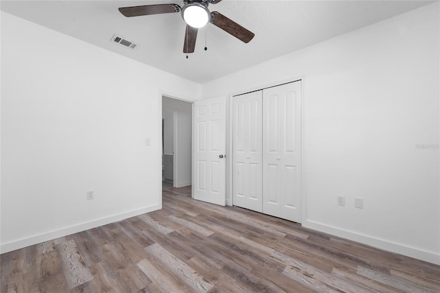 unfurnished bedroom featuring a closet, light hardwood / wood-style floors, and ceiling fan