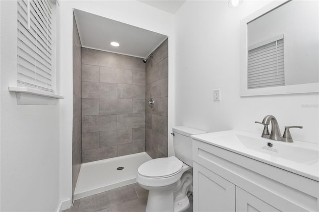 bathroom with toilet, a tile shower, vanity with extensive cabinet space, and tile flooring