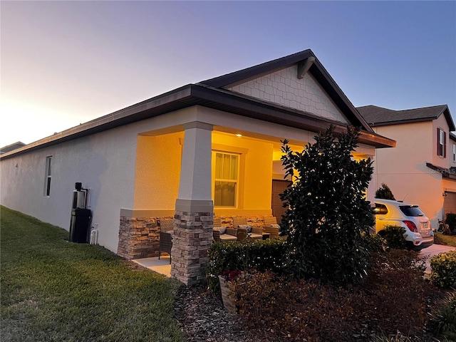 view of side of home featuring covered porch and a yard