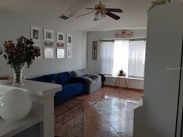 tiled living room featuring ceiling fan and a textured ceiling