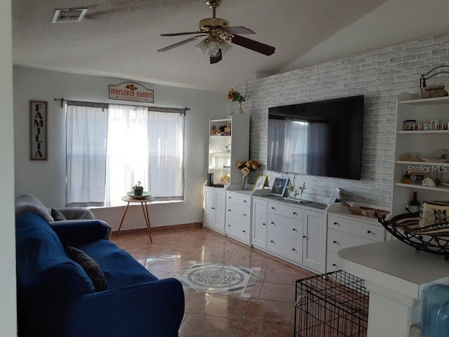 living room featuring ceiling fan, lofted ceiling, a textured ceiling, and light tile patterned floors