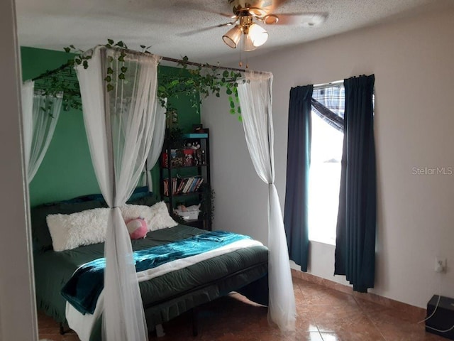 tiled bedroom with ceiling fan and a textured ceiling