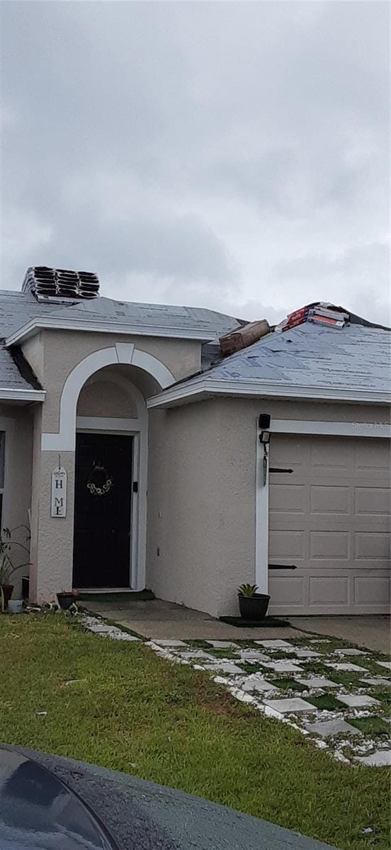 entrance to property featuring a garage and a lawn