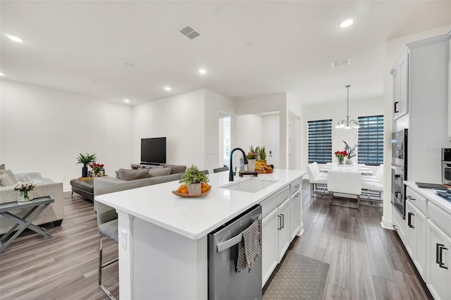 kitchen featuring white cabinets, a kitchen island with sink, dishwasher, and sink