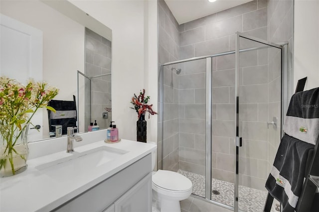 bathroom featuring toilet, vanity, tile patterned flooring, and a shower with shower door