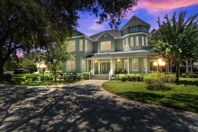 victorian house featuring a porch and a lawn