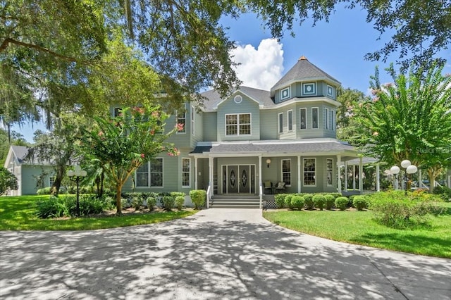 victorian-style house featuring a porch and a front lawn