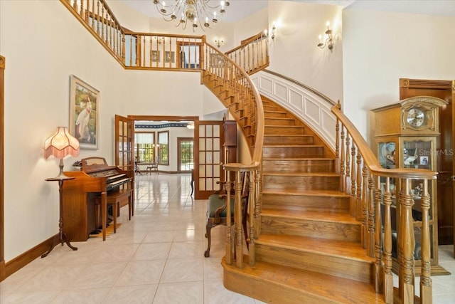 staircase with a towering ceiling, a chandelier, french doors, and light tile flooring