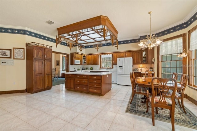 kitchen featuring pendant lighting, ornamental molding, a chandelier, white fridge with ice dispenser, and a center island