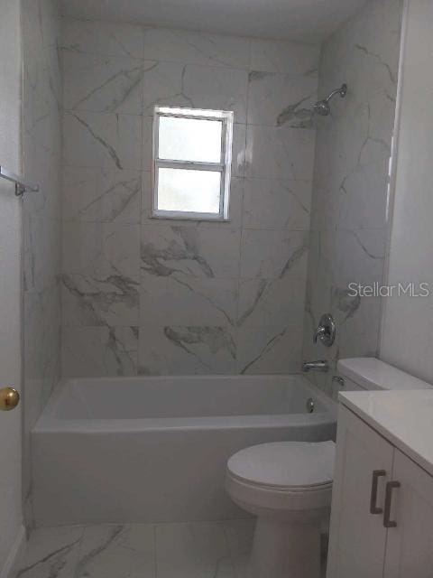 full bathroom featuring tiled shower / bath, vanity, and toilet