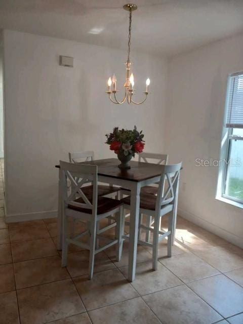 dining area with an inviting chandelier, light tile patterned floors, and a healthy amount of sunlight