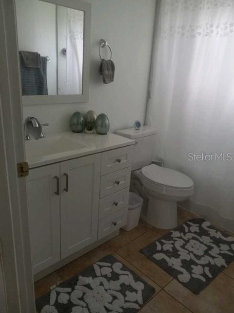 bathroom featuring vanity, toilet, and tile patterned flooring