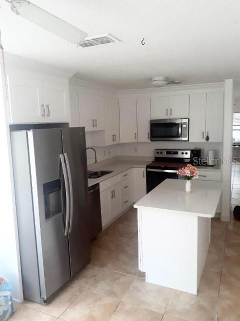 kitchen featuring white cabinetry, appliances with stainless steel finishes, a center island, and sink