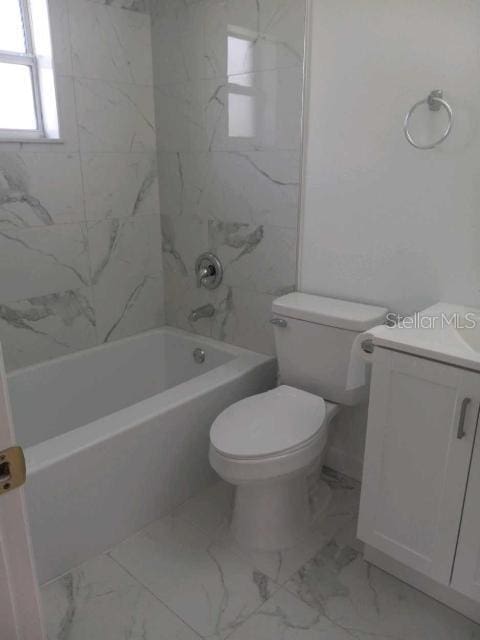 full bathroom featuring tiled shower / bath, vanity, and toilet