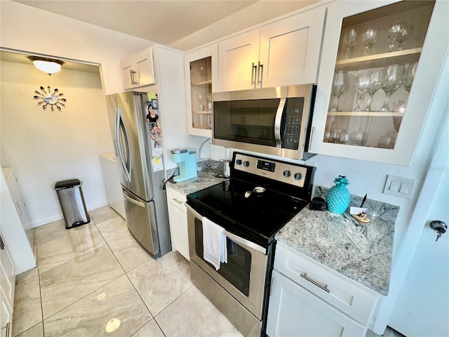 kitchen with light tile floors, white cabinets, light stone counters, and stainless steel appliances