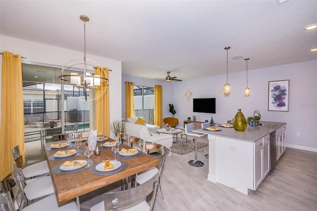 dining room featuring a textured ceiling, ceiling fan with notable chandelier, wine cooler, light wood-type flooring, and sink