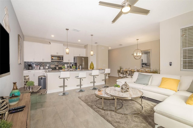 living room featuring light hardwood / wood-style floors and ceiling fan with notable chandelier