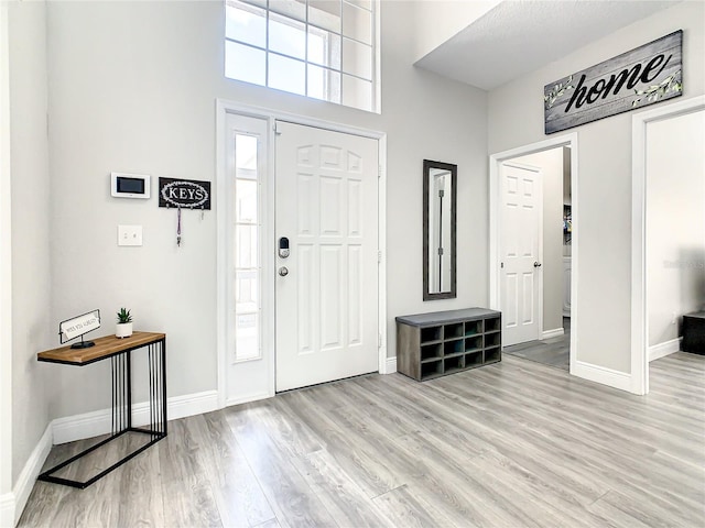 foyer entrance featuring light hardwood / wood-style flooring and a towering ceiling