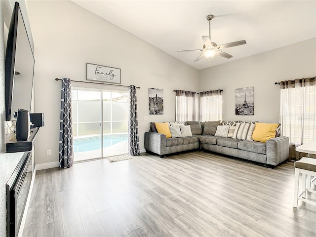 living room with high vaulted ceiling, light hardwood / wood-style floors, a fireplace, and ceiling fan